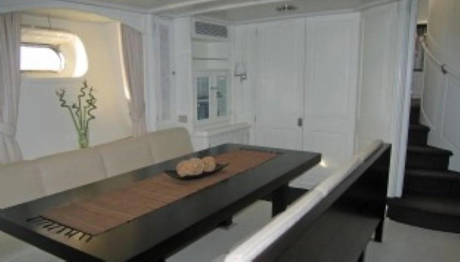 The yacht's dining area features a sleek black table with comfortable seating and elegant decor. aboard MARI-CHA III Yacht for Sale