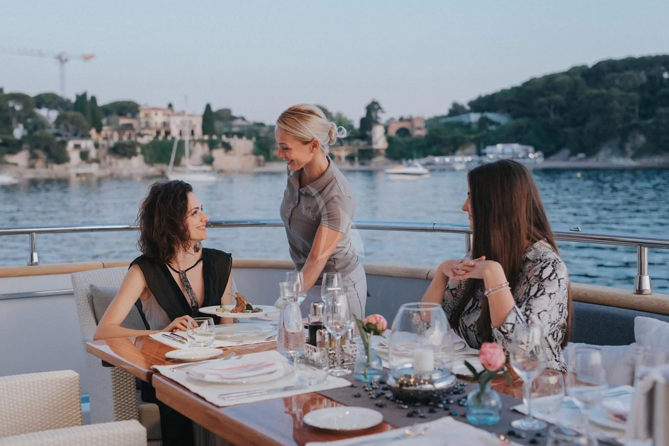 Guests enjoy a meal on the aft deck with a scenic waterfront view. aboard TALILA Yacht for Sale