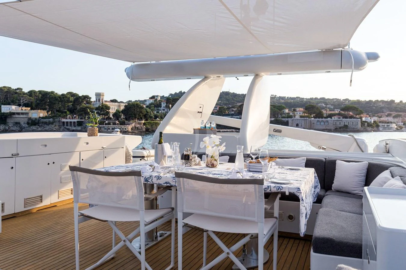 The aft deck features a stylish dining area with a view of the surrounding coastline. aboard TALILA Yacht for Sale