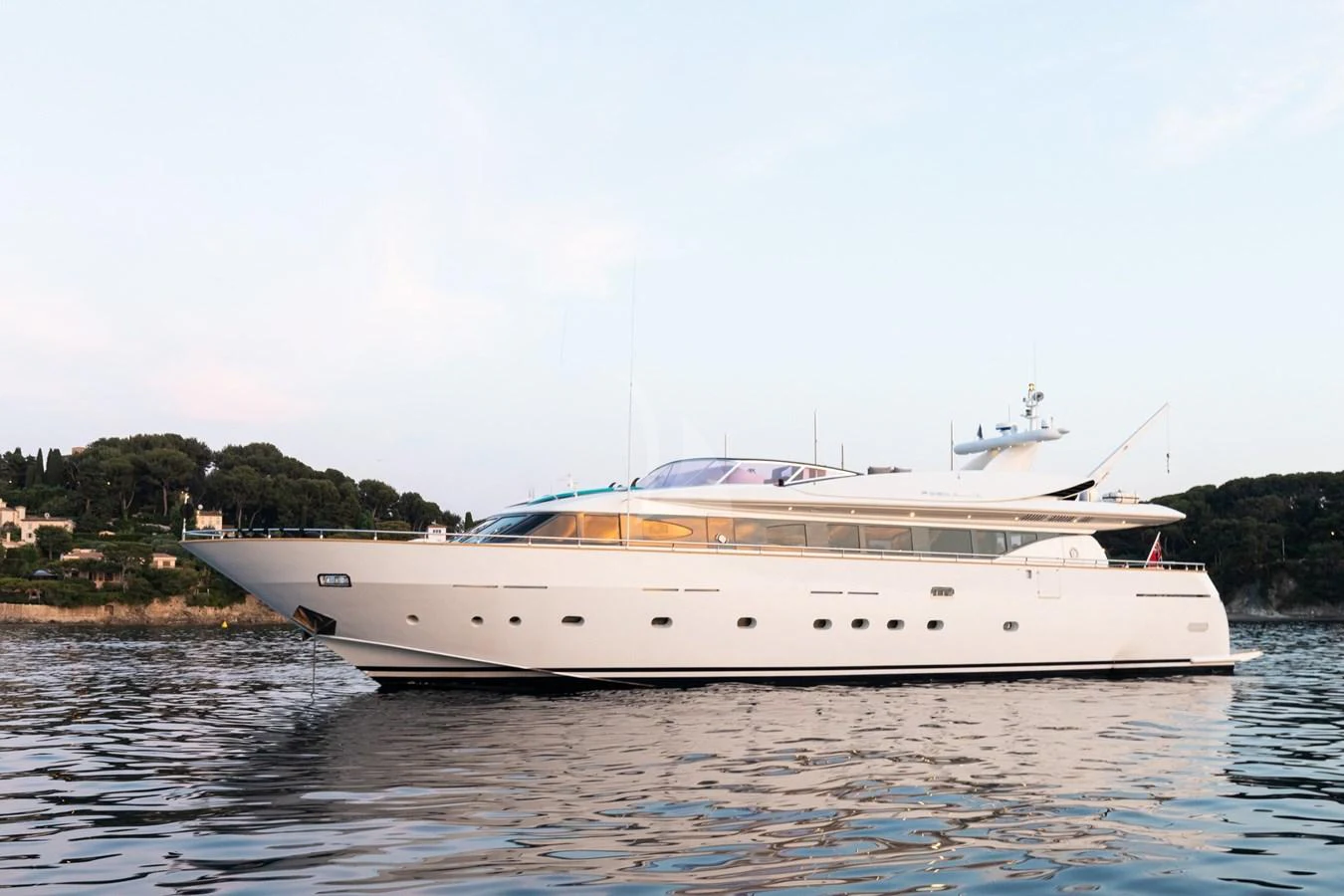 A sleek and elegant yacht glides gracefully on calm waters near a picturesque shoreline. aboard TALILA Yacht for Sale