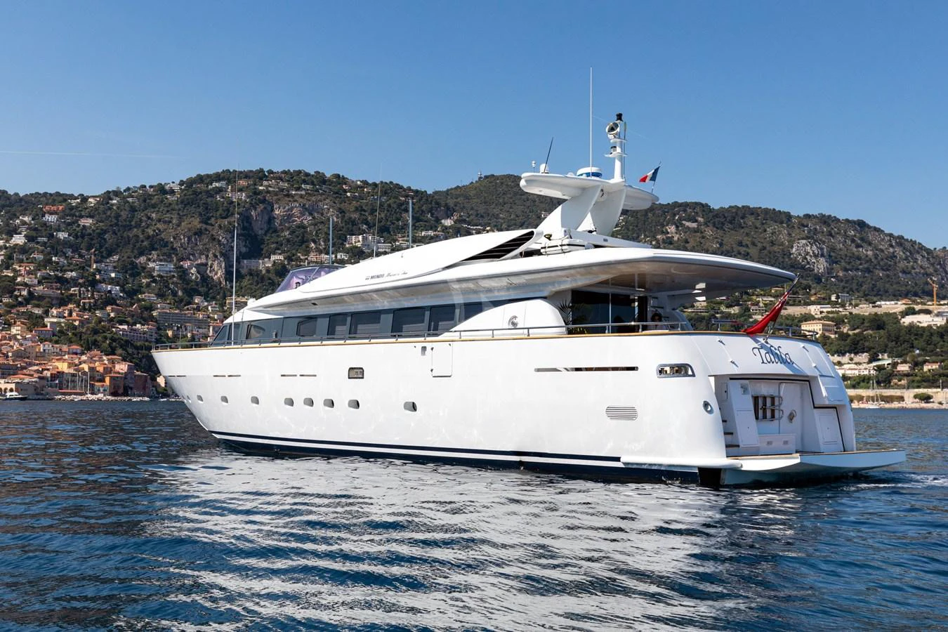 A sleek and modern yacht glides gracefully on the water with a scenic coastal backdrop. aboard TALILA Yacht for Sale