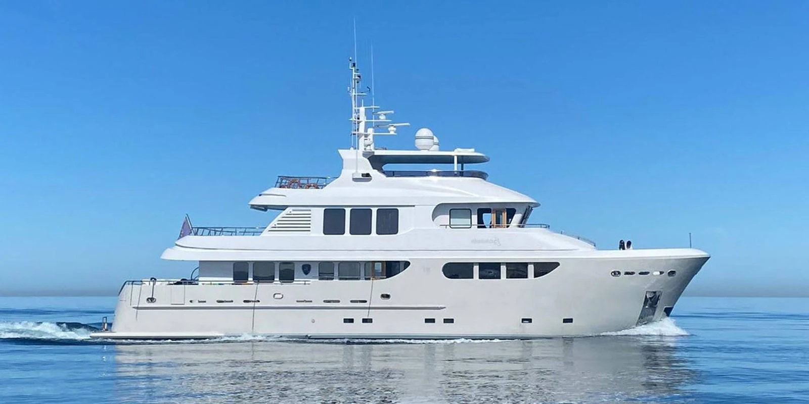 A luxurious yacht cruising on calm, clear blue waters under a bright sky. aboard BANDIDO Yacht for Sale