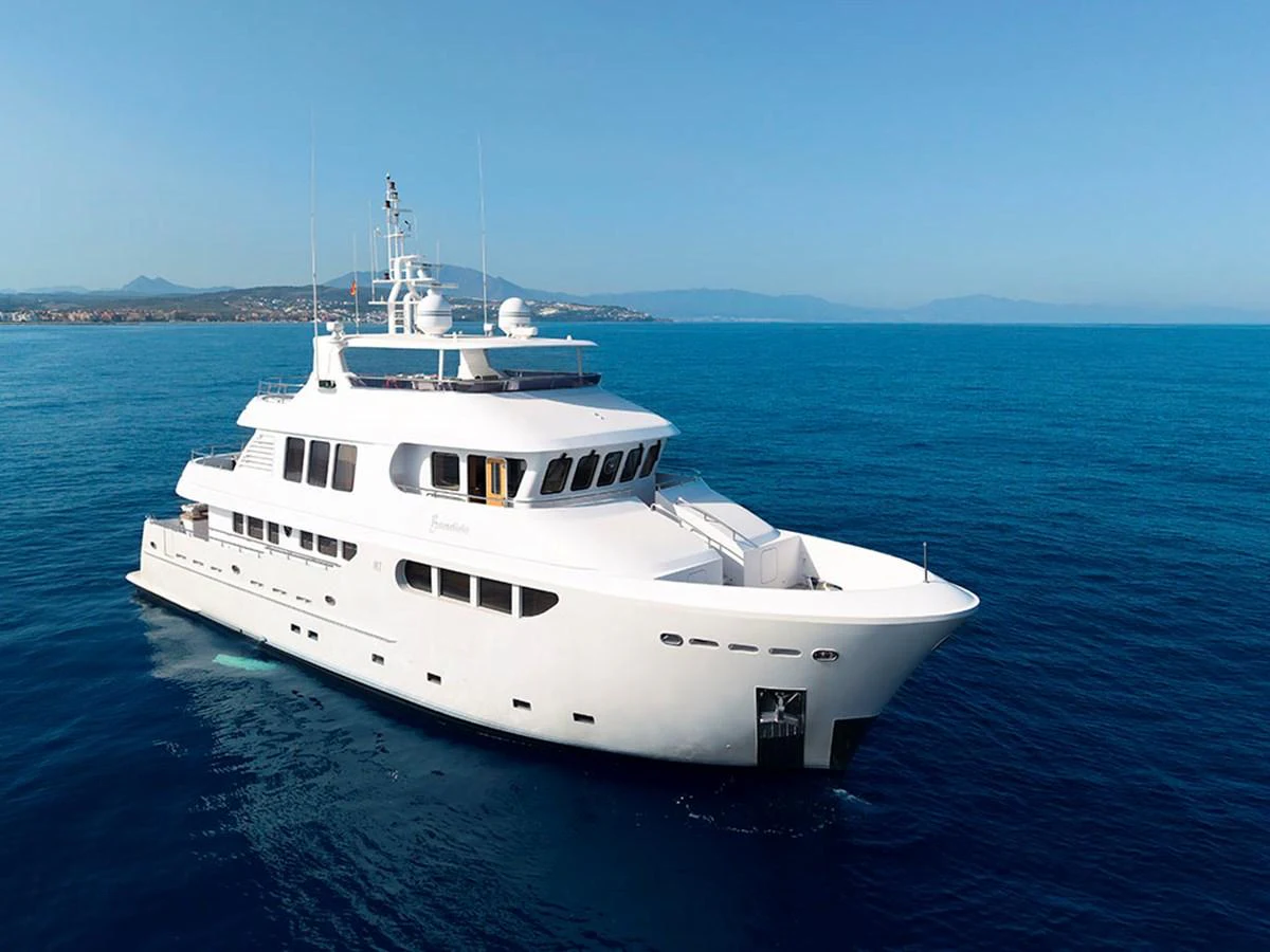 A pristine white yacht glides gracefully on calm blue waters under a clear sky. aboard BANDIDO Yacht for Sale