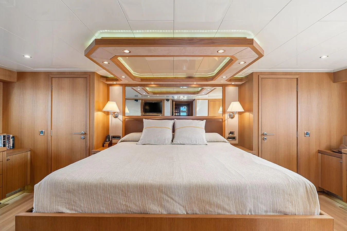 The master stateroom features a spacious bed with elegant wood paneling and ambient lighting. aboard BANDIDO Yacht for Sale