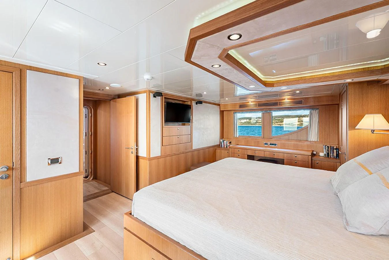The master stateroom features a spacious bed, ample natural light, and elegant wood finishes. aboard BANDIDO Yacht for Sale