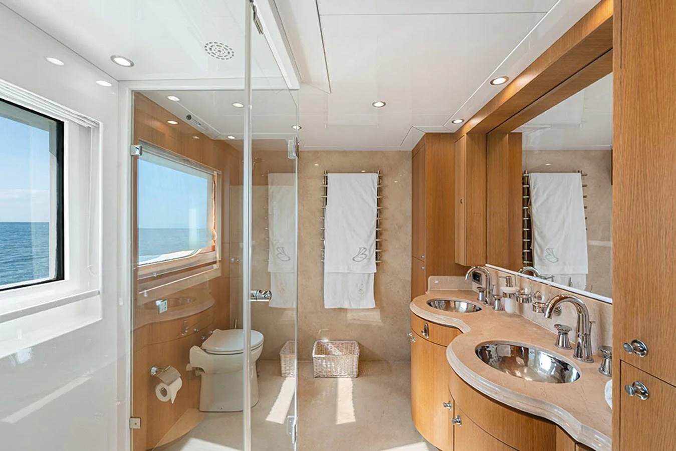 The yacht's bathroom features elegant wooden cabinetry, dual sinks, and a large window with an ocean view. aboard BANDIDO Yacht for Sale