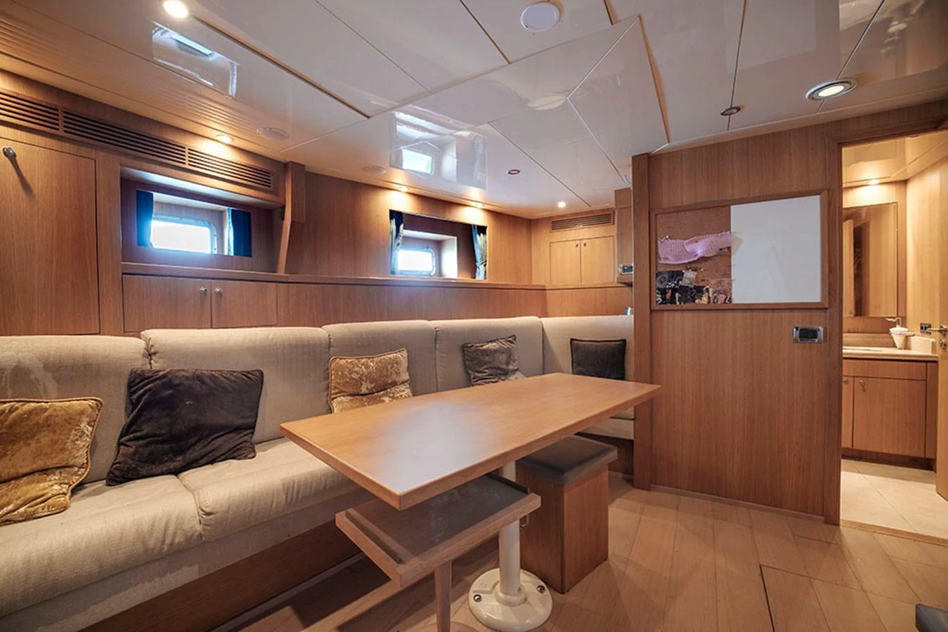 The yacht's salon features a cozy seating area with a wooden table and ample natural light. aboard BANDIDO Yacht for Sale