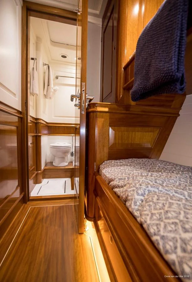 A cozy yacht bathroom with wooden finishes and a small bunk area. aboard ACADIA Yacht for Sale