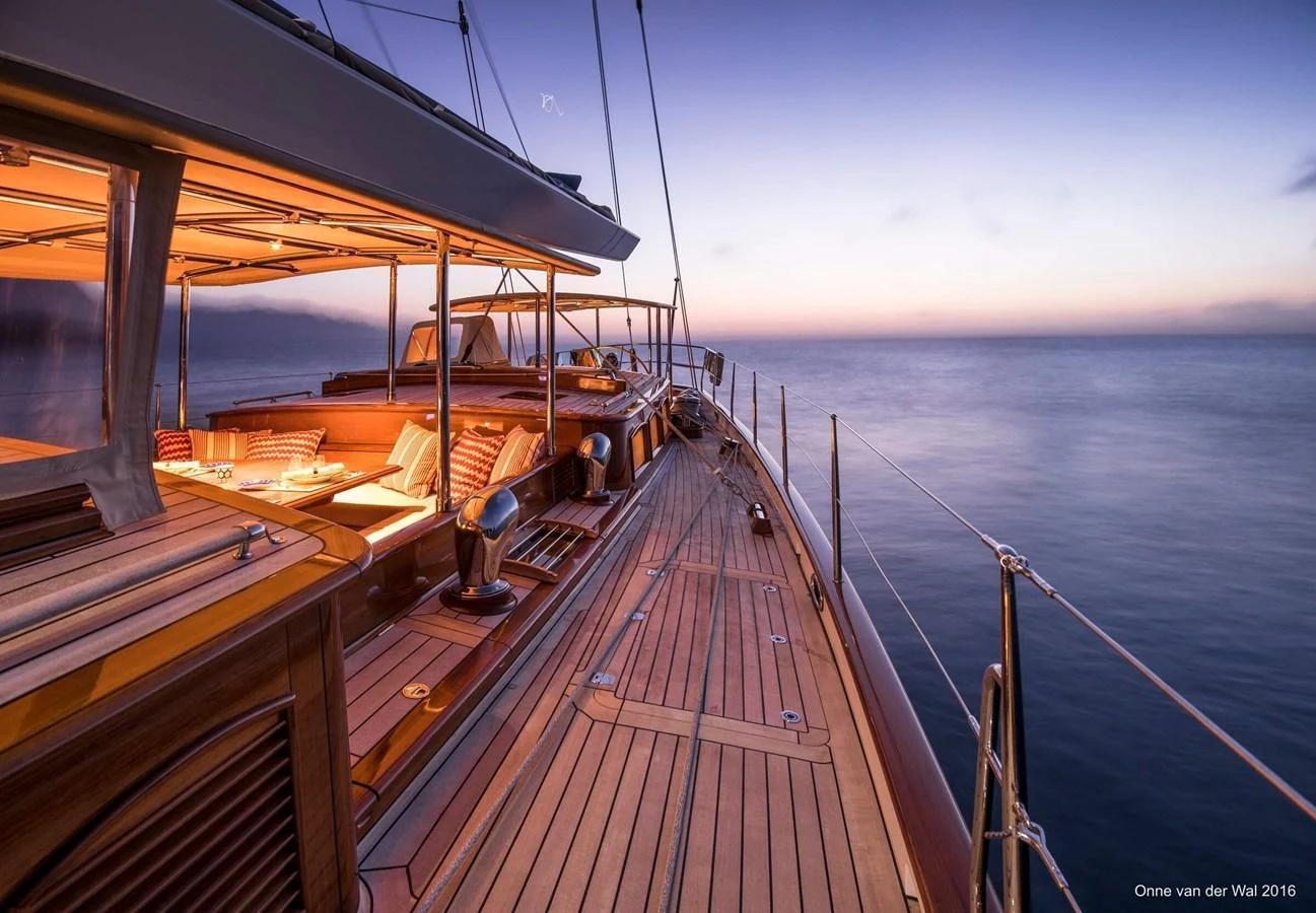 The yacht's deck is beautifully illuminated at sunset, showcasing its elegant wooden finishes and comfortable seating areas. aboard ACADIA Yacht for Sale