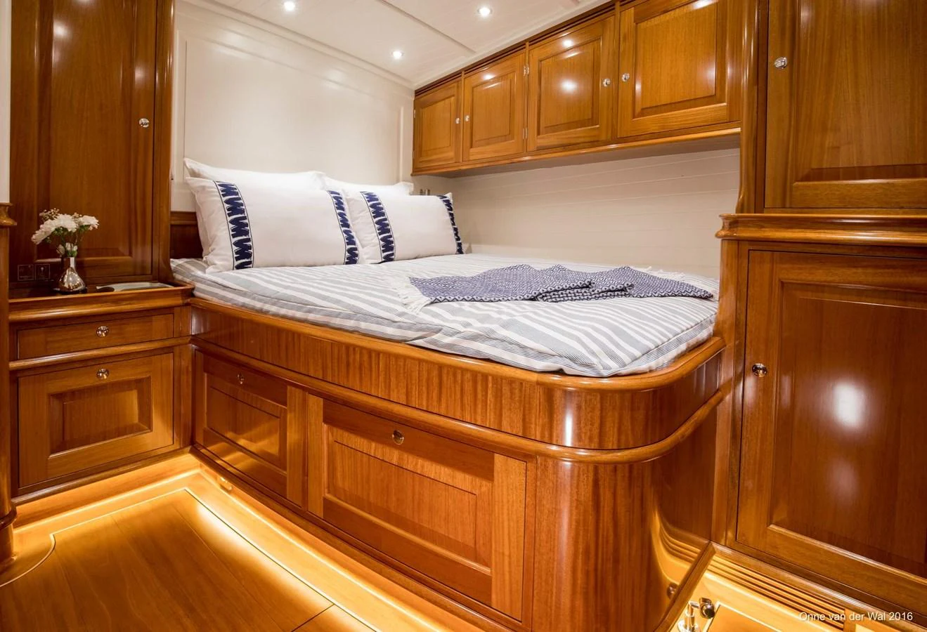 The stateroom features luxurious wooden cabinetry and a cozy bed with elegant bedding. aboard ACADIA Yacht for Sale