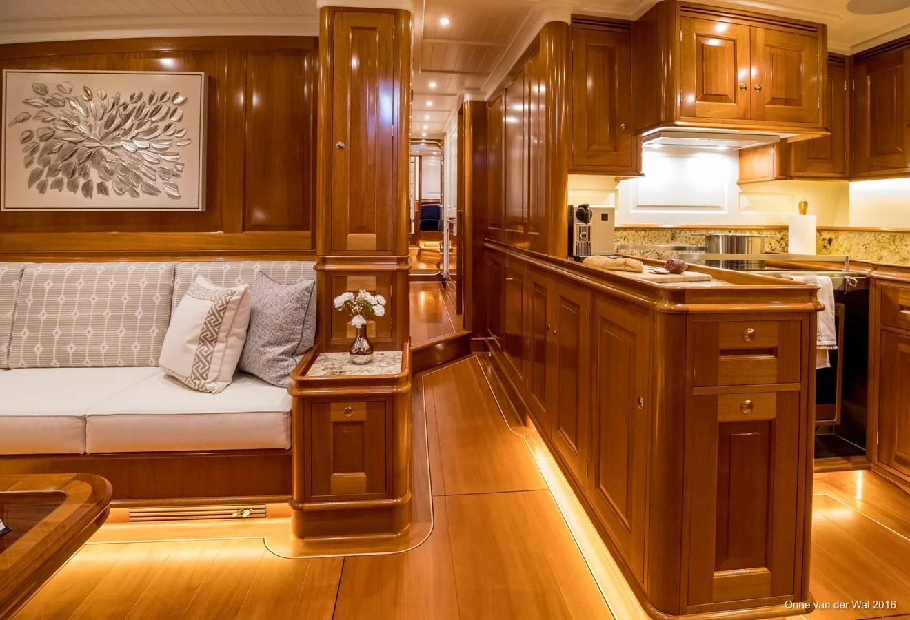 The yacht's salon features elegant wooden cabinetry, plush seating, and warm ambient lighting. aboard ACADIA Yacht for Sale