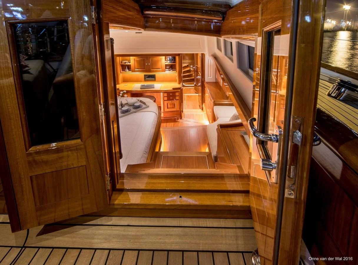 The image showcases a warmly lit cabin with wooden finishes and a cozy bed. aboard ACADIA Yacht for Sale