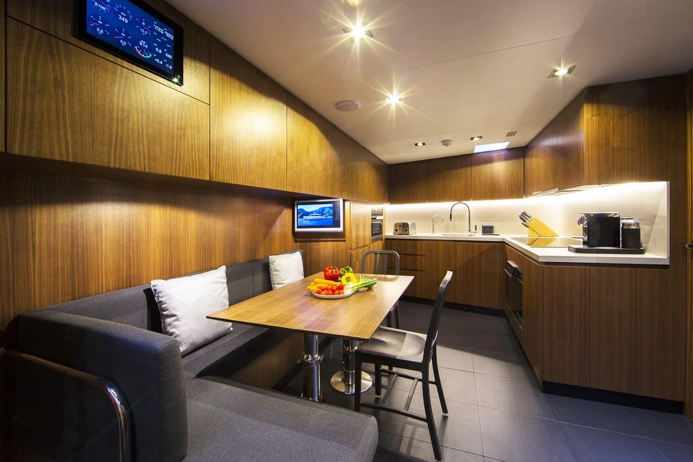 The yacht's galley features modern wooden cabinetry, a cozy dining area, and state-of-the-art appliances. aboard CASA Yacht for Sale