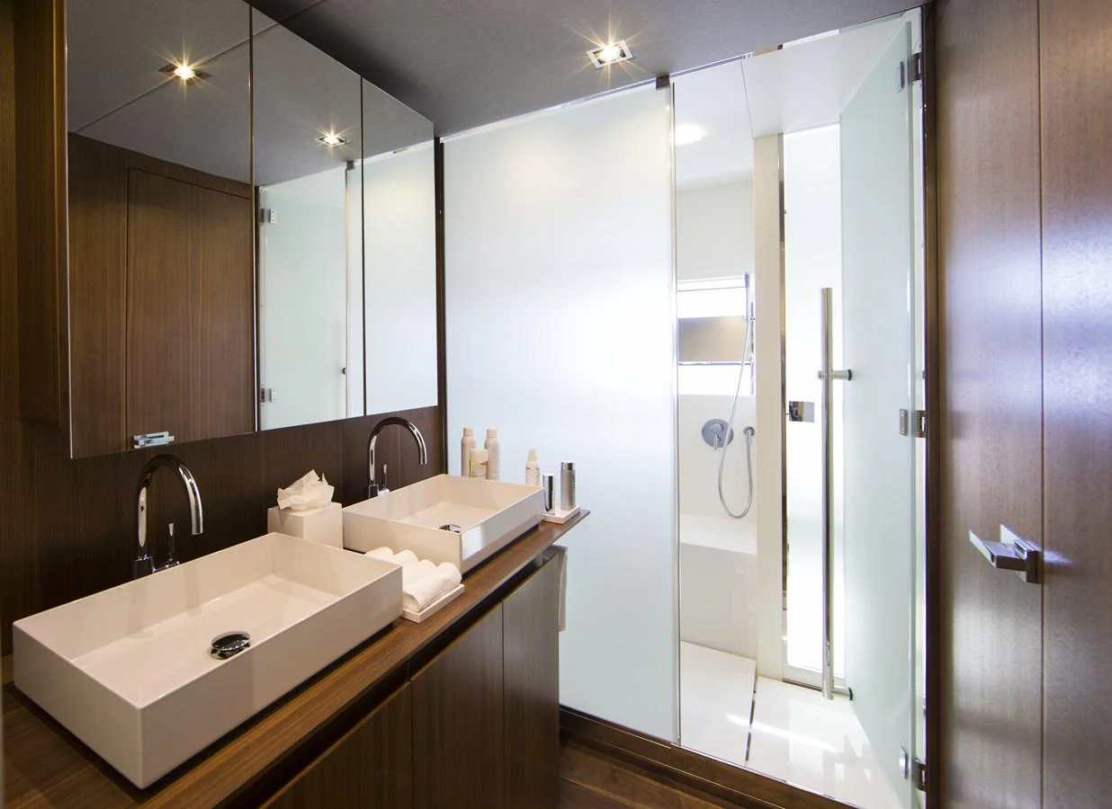 The yacht's bathroom features a modern design with dual sinks and a glass-enclosed shower. aboard CASA Yacht for Sale