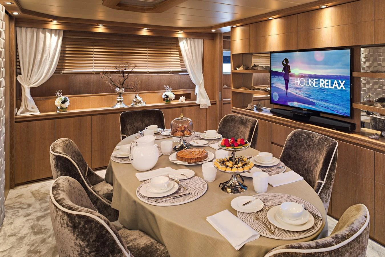 The elegant dining area features a beautifully set table and a large TV for entertainment. aboard AMAYA Yacht for Sale
