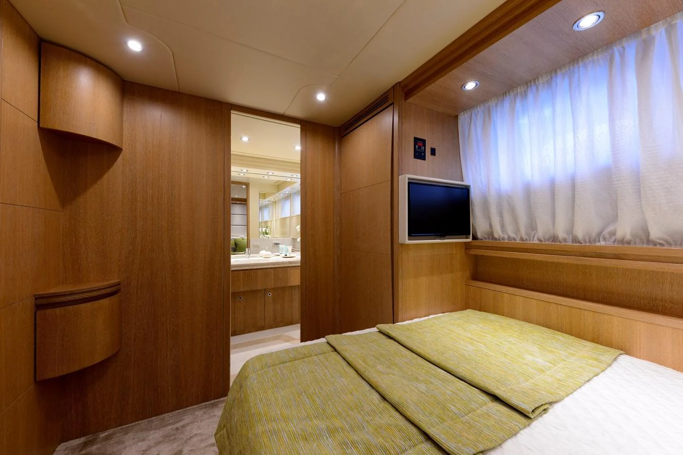 A cozy stateroom featuring a comfortable bed, wooden cabinetry, and a wall-mounted TV. aboard AMAYA Yacht for Sale