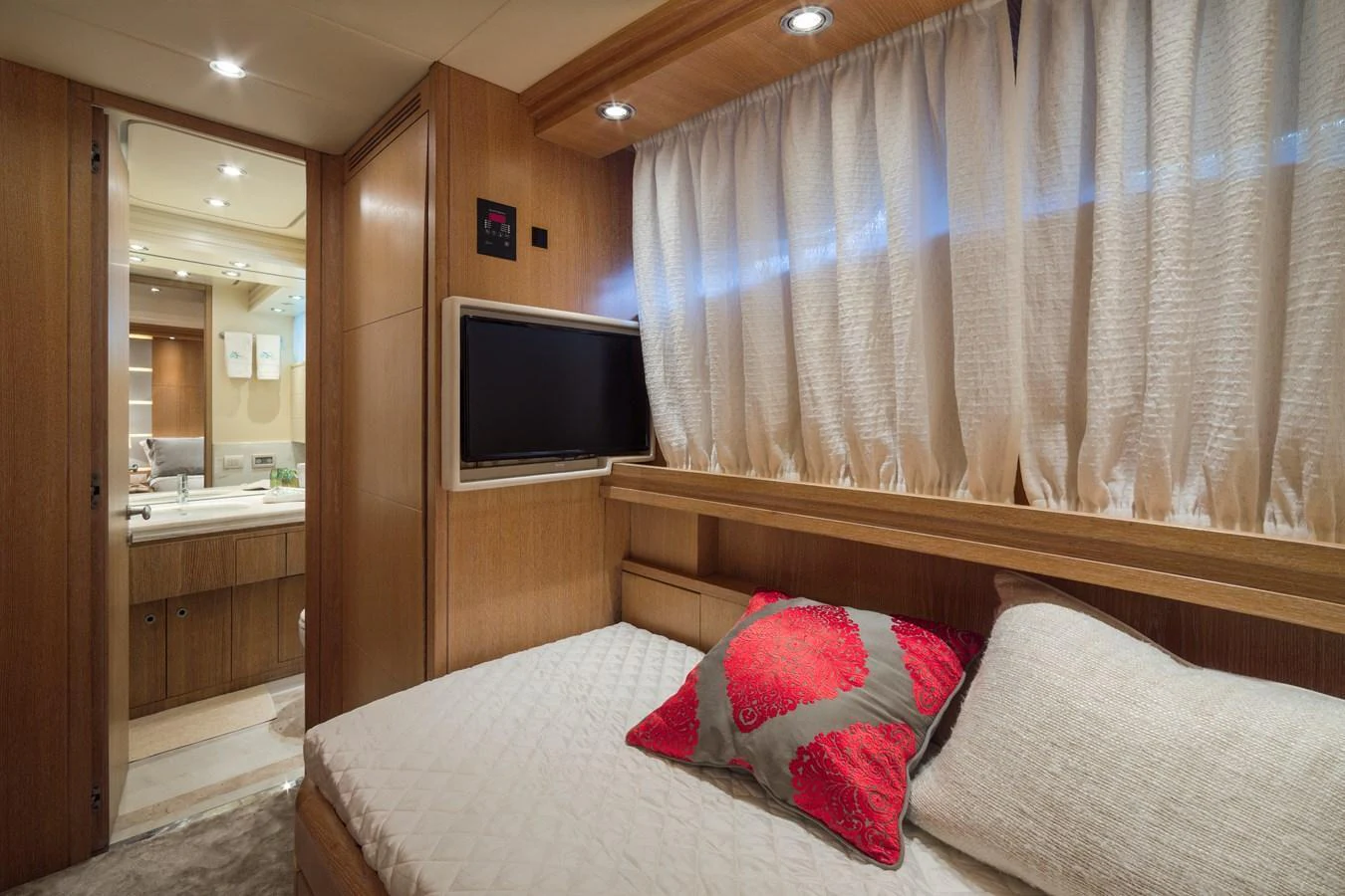 A cozy guest cabin featuring a comfortable bed, a wall-mounted TV, and elegant wooden finishes. aboard AMAYA Yacht for Sale