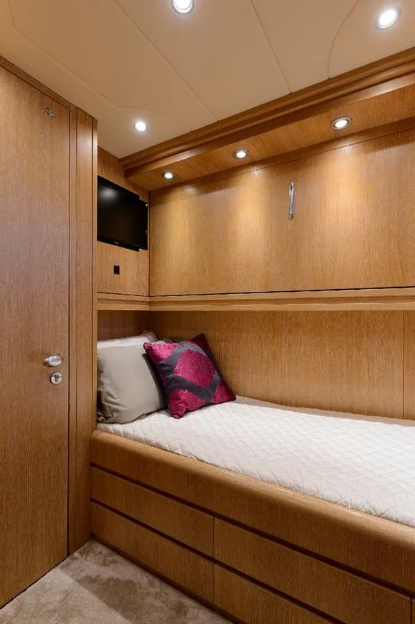 A cozy guest cabin featuring a single bed with elegant wood paneling and ambient lighting. aboard AMAYA Yacht for Sale