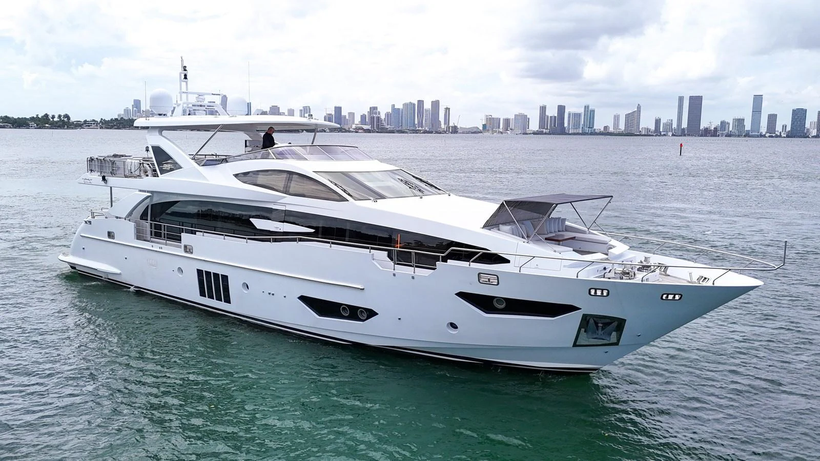A sleek and modern yacht cruising on calm waters with a city skyline in the background. aboard 2017 AZIMUT 30 METRI Yacht for Sale