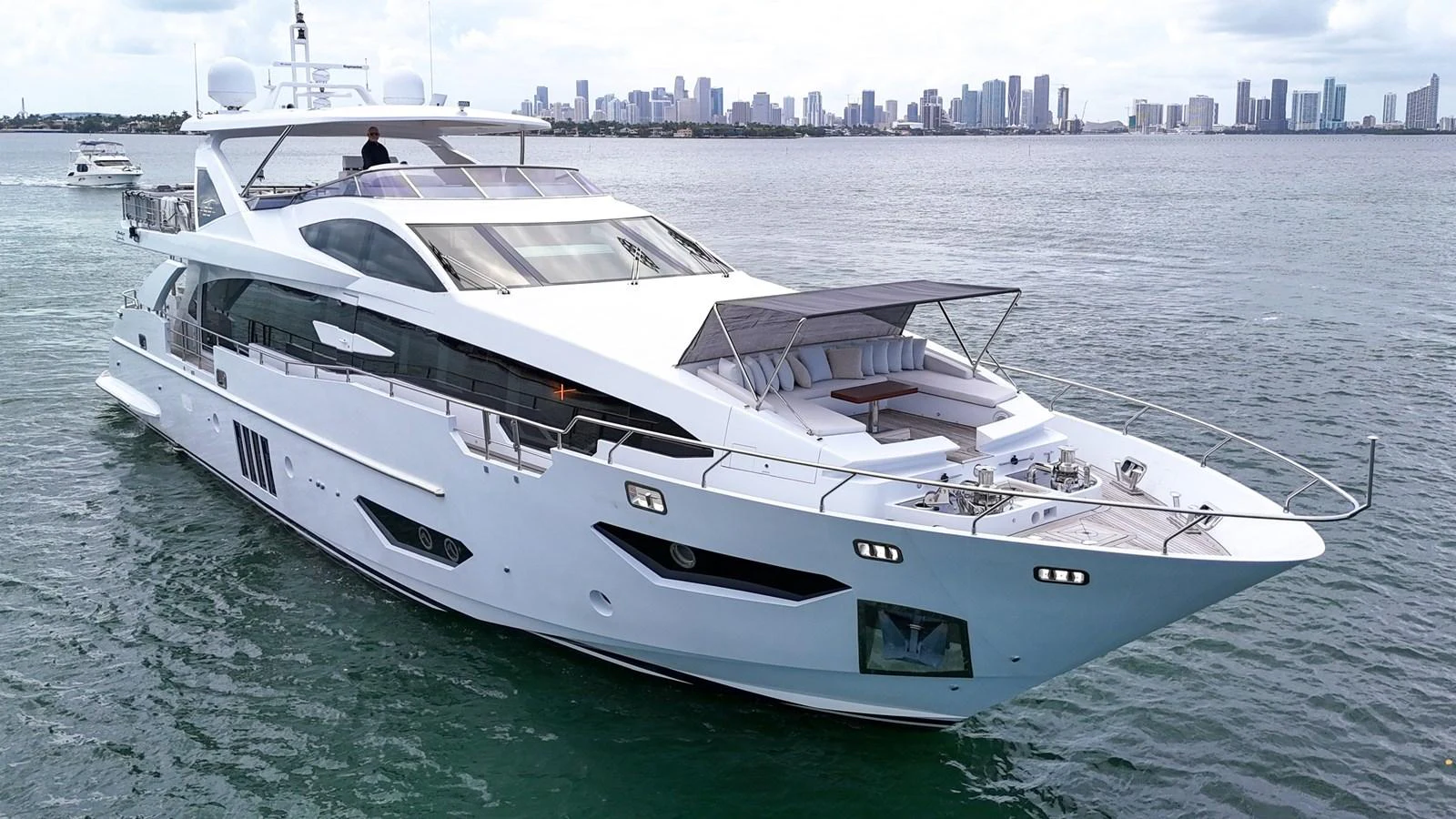 A sleek and modern yacht cruising on calm waters with a city skyline in the background. aboard 2017 AZIMUT 30 METRI Yacht for Sale