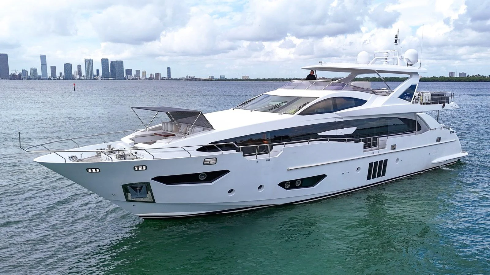 A sleek and modern yacht glides gracefully on the water with a city skyline in the background. aboard 2017 AZIMUT 30 METRI Yacht for Sale
