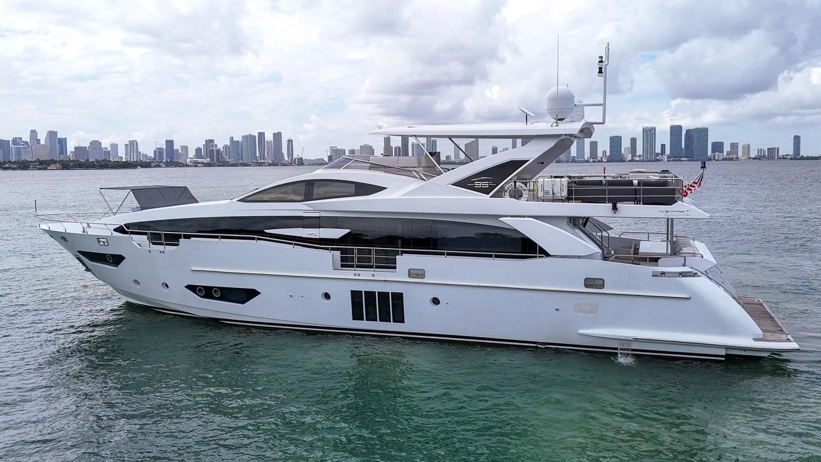 A sleek and modern yacht cruising near a city skyline. aboard 2017 AZIMUT 30 METRI Yacht for Sale