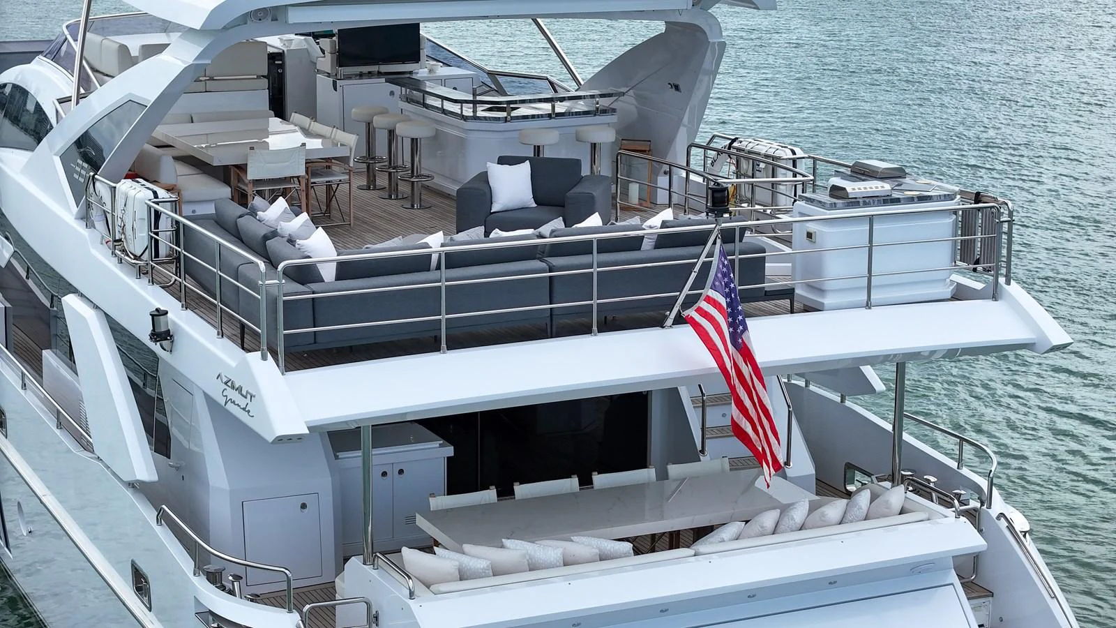 The yacht's aft deck features multiple lounging areas and an American flag, offering a luxurious outdoor living space. aboard 2017 AZIMUT 30 METRI Yacht for Sale