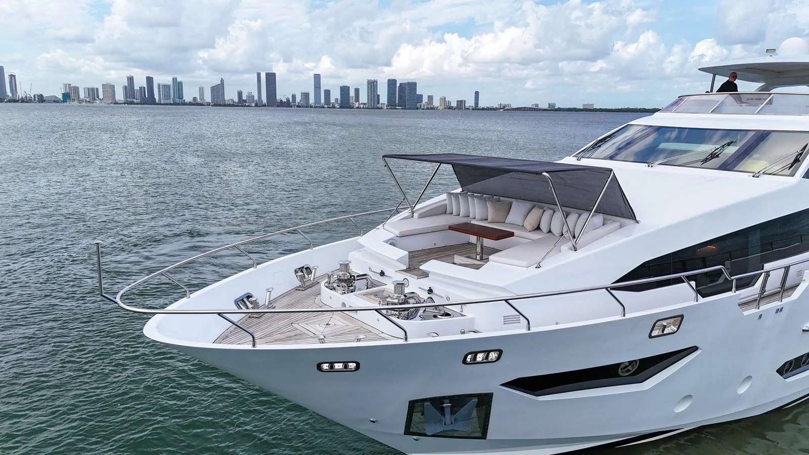 A sleek yacht cruising near a city skyline with a spacious foredeck lounge area. aboard 2017 AZIMUT 30 METRI Yacht for Sale