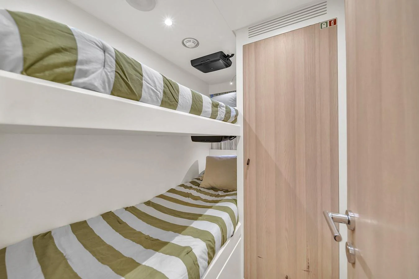 The crew cabin features compact bunk beds with striped bedding and a wooden door for privacy. aboard 2017 AZIMUT 30 METRI Yacht for Sale