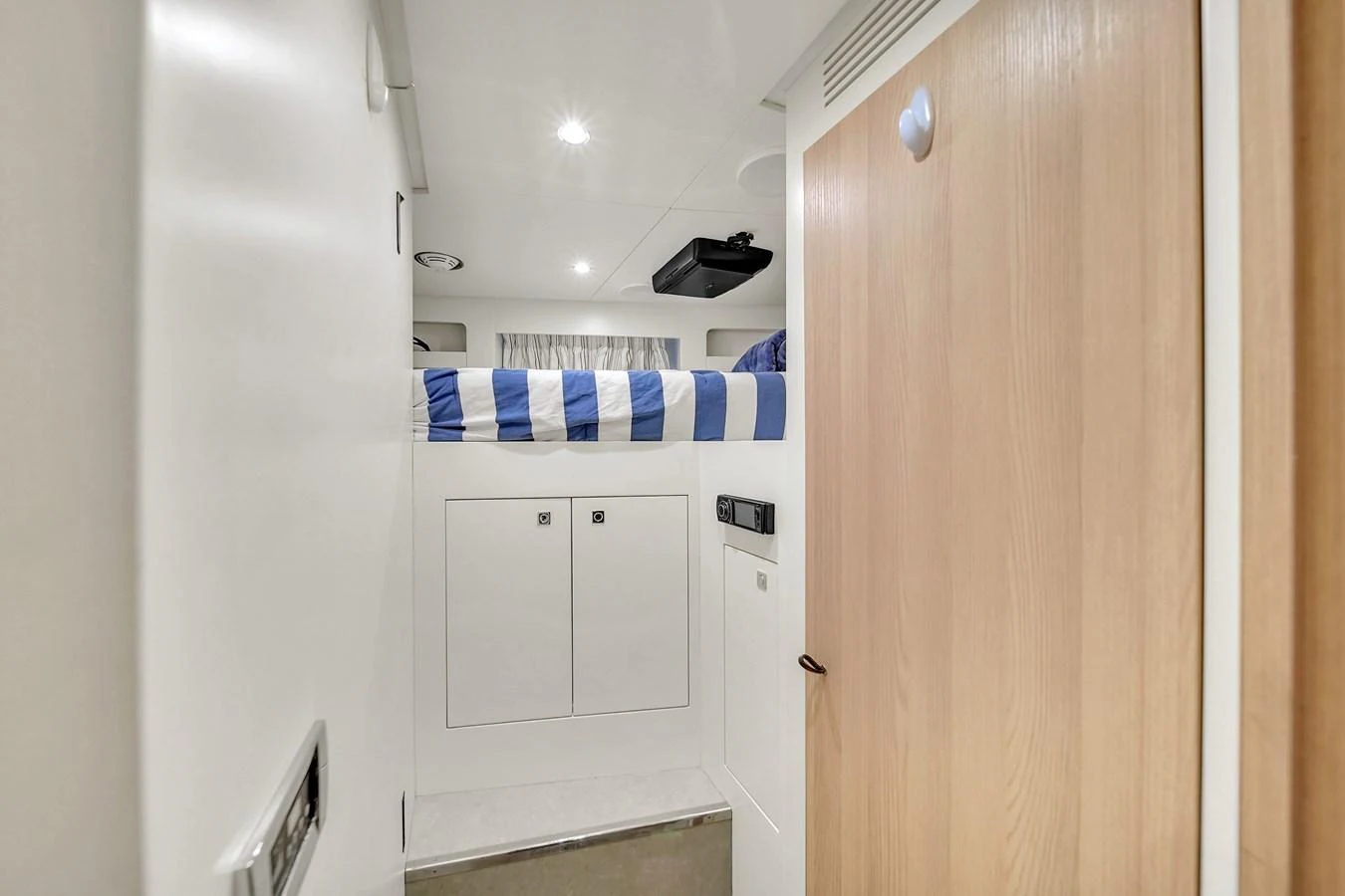 A cozy yacht cabin featuring a bunk bed with striped bedding and ample storage space. aboard 2017 AZIMUT 30 METRI Yacht for Sale