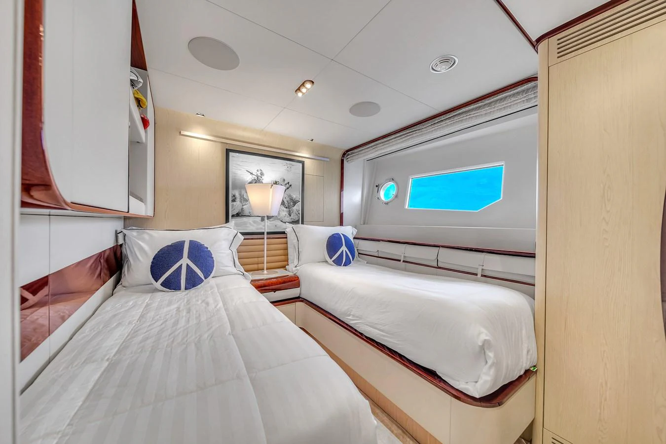 The guest stateroom features twin beds with peace sign pillows and a large window offering a view of the sea. aboard 2017 AZIMUT 30 METRI Yacht for Sale