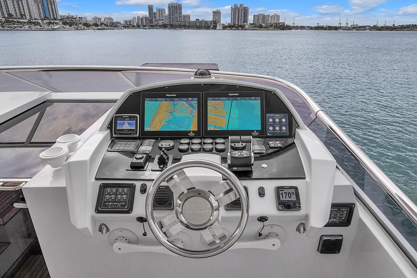 The helm station offers advanced navigation equipment with a stunning waterfront backdrop. aboard 2017 AZIMUT 30 METRI Yacht for Sale