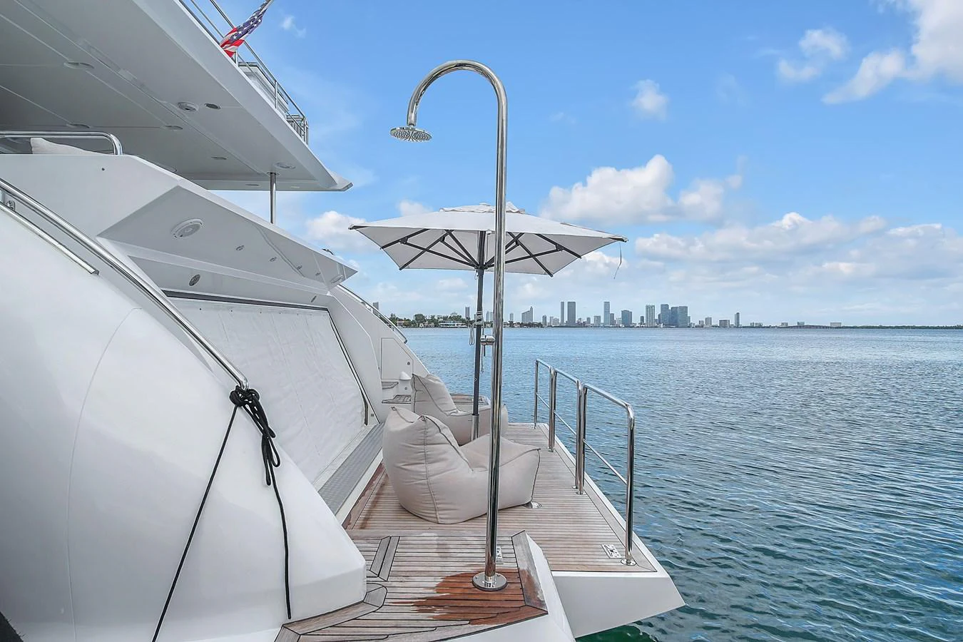 The yacht's swim platform features a luxurious setup with a shower, umbrella, and comfortable seating, offering a perfect spot to relax by the water. aboard 2017 AZIMUT 30 METRI Yacht for Sale