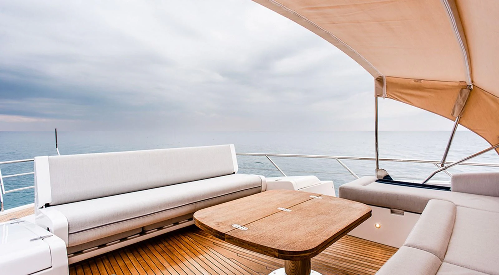The aft deck offers a serene seating area with a wooden table and cushioned benches, perfect for enjoying the sea views. aboard LASTOCHKA Yacht for Sale