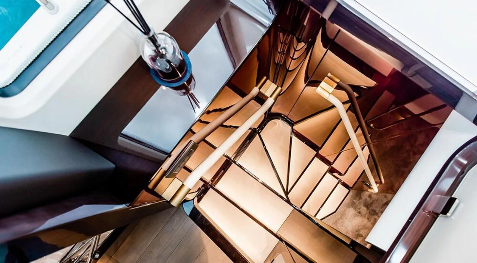 A luxurious staircase with sleek, modern design elements and reflective surfaces. aboard LASTOCHKA Yacht for Sale