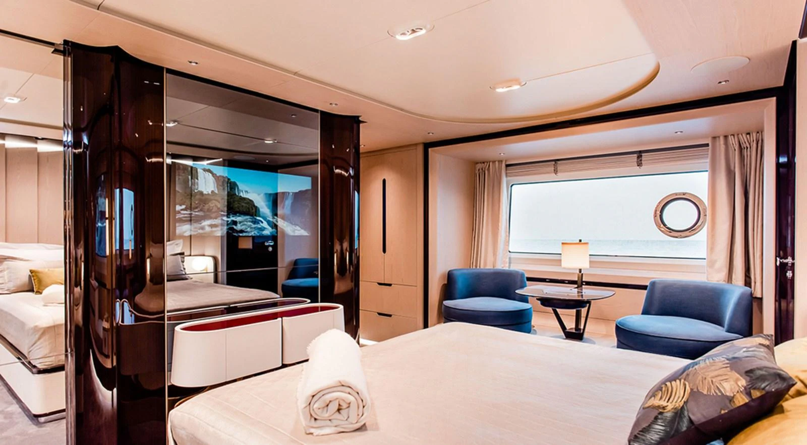 A luxurious stateroom featuring a large bed, seating area, and ample natural light from a large window. aboard LASTOCHKA Yacht for Sale