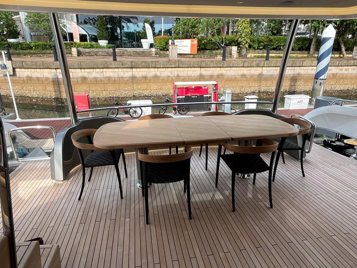 The aft deck features a stylish dining area with a wooden table and modern chairs, perfect for alfresco dining. aboard LILYAN Yacht for Sale