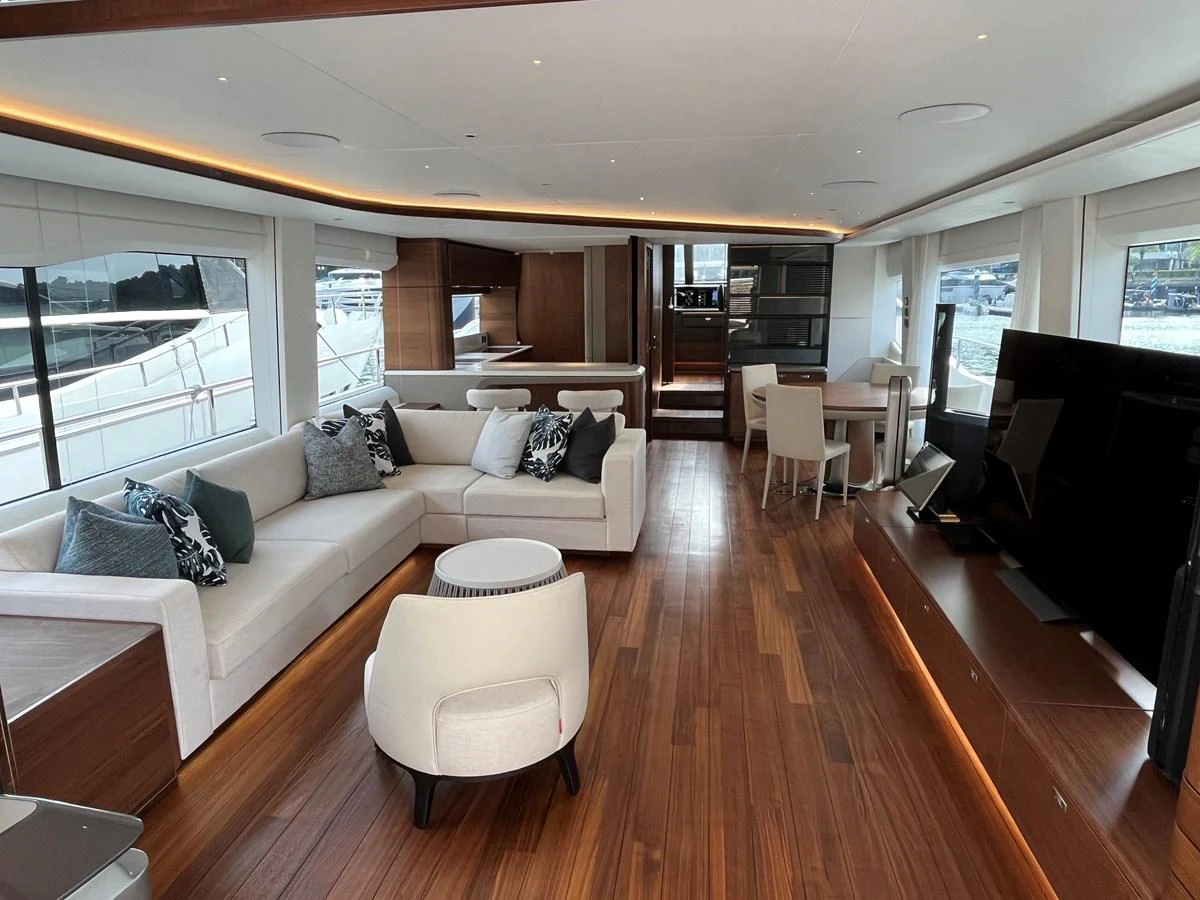 The spacious salon features elegant seating, a large TV, and ample natural light from the surrounding windows. aboard LILYAN Yacht for Sale