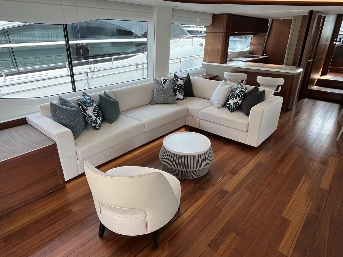 The salon features a spacious and elegant seating area with modern furnishings and large windows offering a view of the marina. aboard LILYAN Yacht for Sale