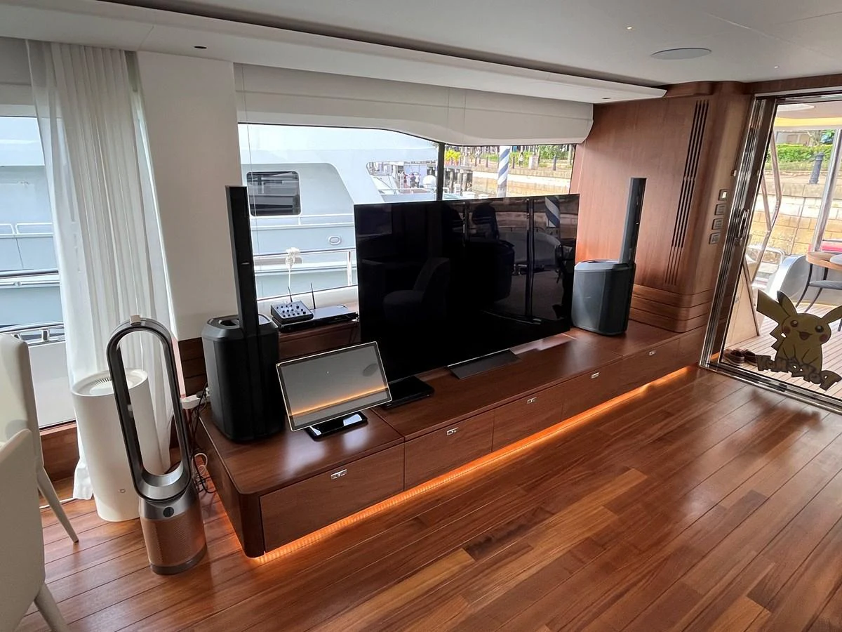The salon features a modern entertainment setup with a large TV and sleek wooden flooring. aboard LILYAN Yacht for Sale