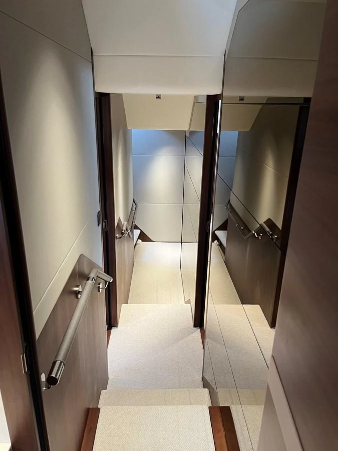 A sleek and modern interior staircase with wooden accents and stainless steel handrails. aboard LILYAN Yacht for Sale