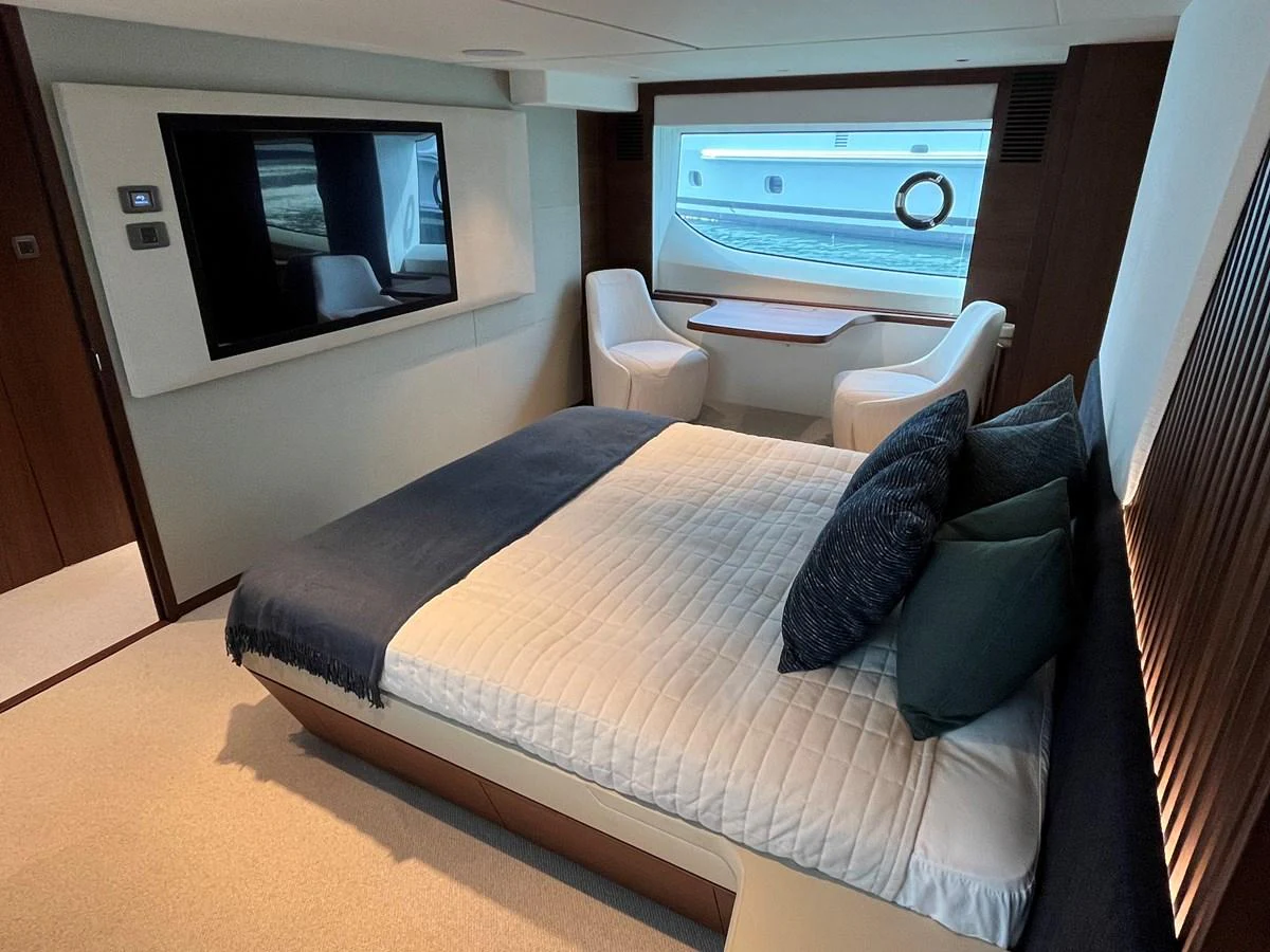 The stateroom features a luxurious bed, a large window, and a cozy seating area with a table. aboard LILYAN Yacht for Sale