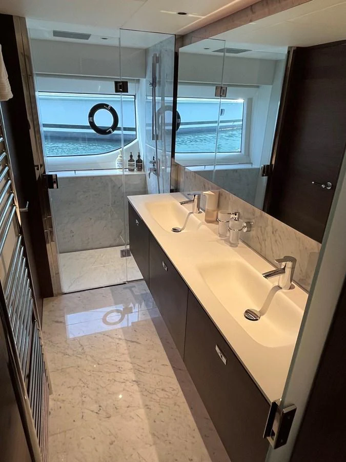 The yacht's bathroom features a double sink vanity with a large mirror and a glass-enclosed shower area. aboard LILYAN Yacht for Sale