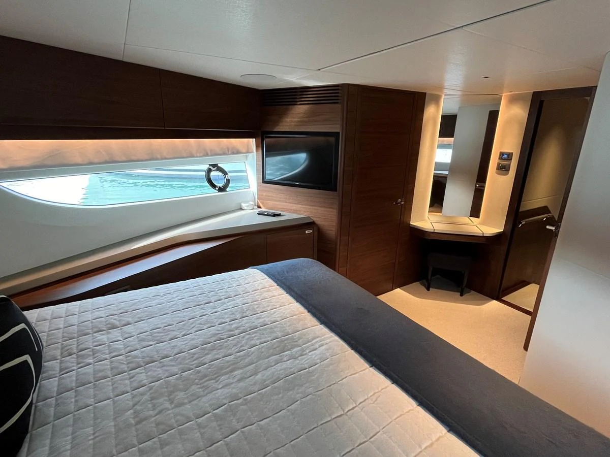 The stateroom features a luxurious bed, a large window with a view, and elegant wood finishes. aboard LILYAN Yacht for Sale