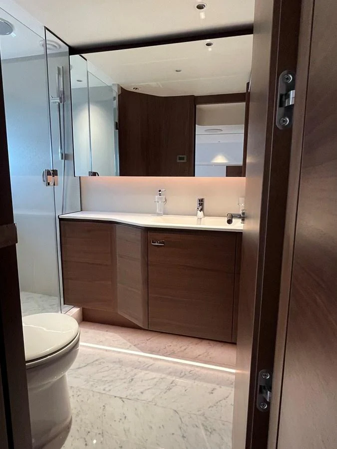 A modern yacht bathroom with sleek wooden cabinetry and a glass-enclosed shower. aboard LILYAN Yacht for Sale