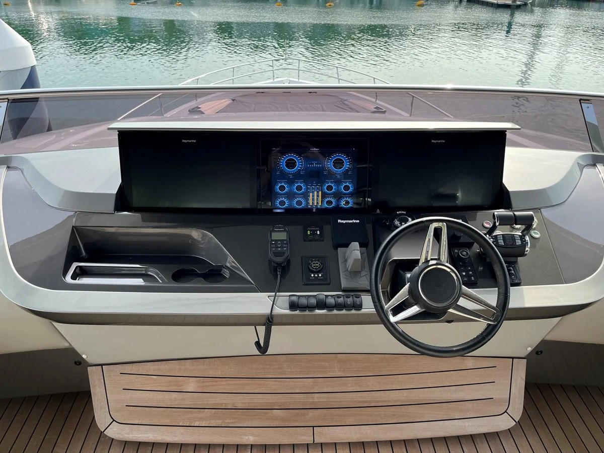 The helm station features advanced navigation equipment and a sleek steering wheel, set against a backdrop of serene waters. aboard LILYAN Yacht for Sale