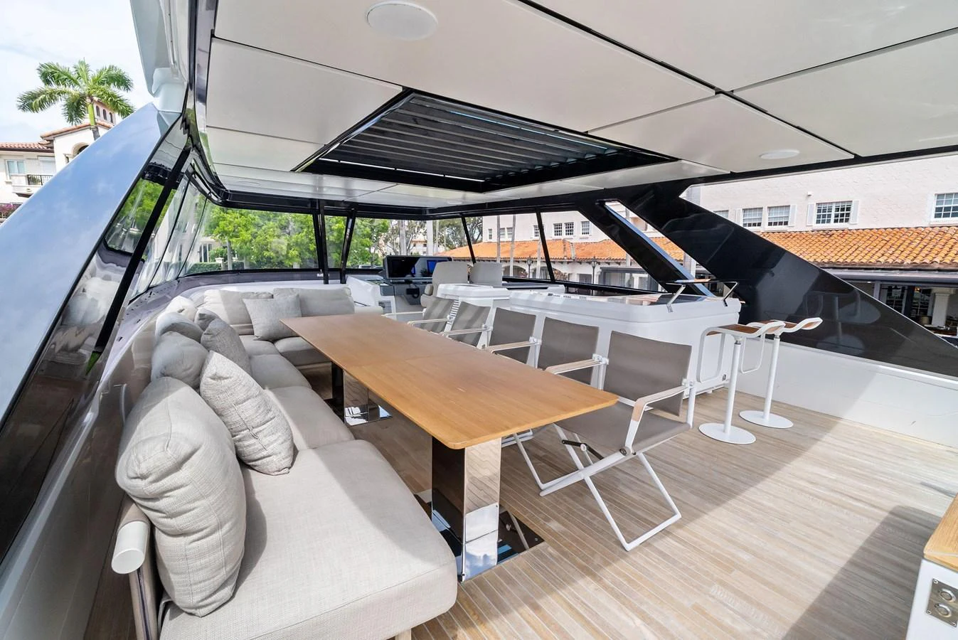 The flybridge features a spacious seating area with a dining table and bar stools, perfect for outdoor relaxation and dining. aboard LADY F Yacht for Sale
