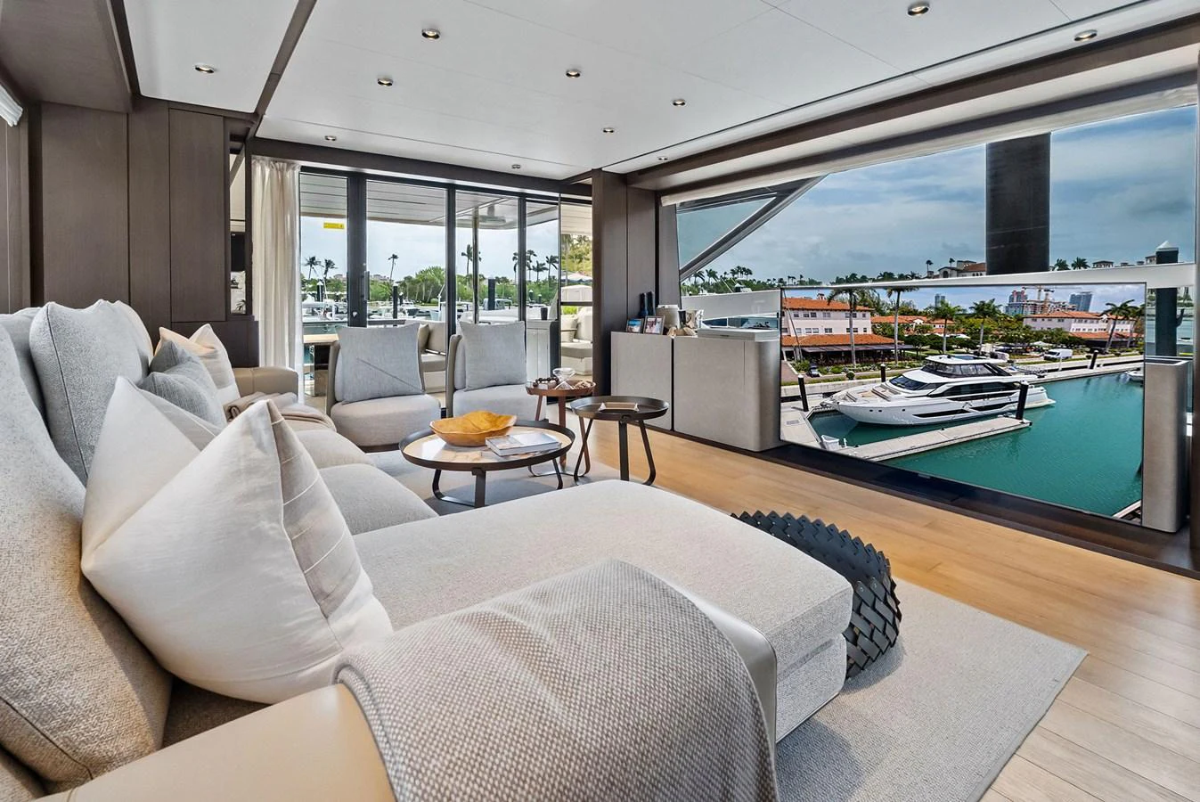 A luxurious interior lounge area with a view of the marina through large windows. aboard LADY F Yacht for Sale