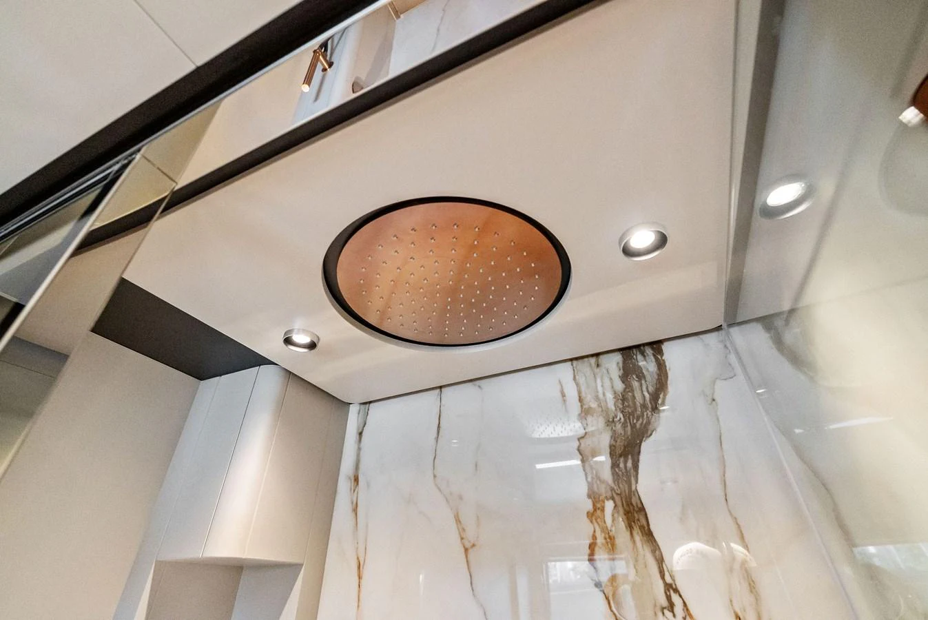 A luxurious rain showerhead is set against an elegant marble backdrop. aboard LADY F Yacht for Sale