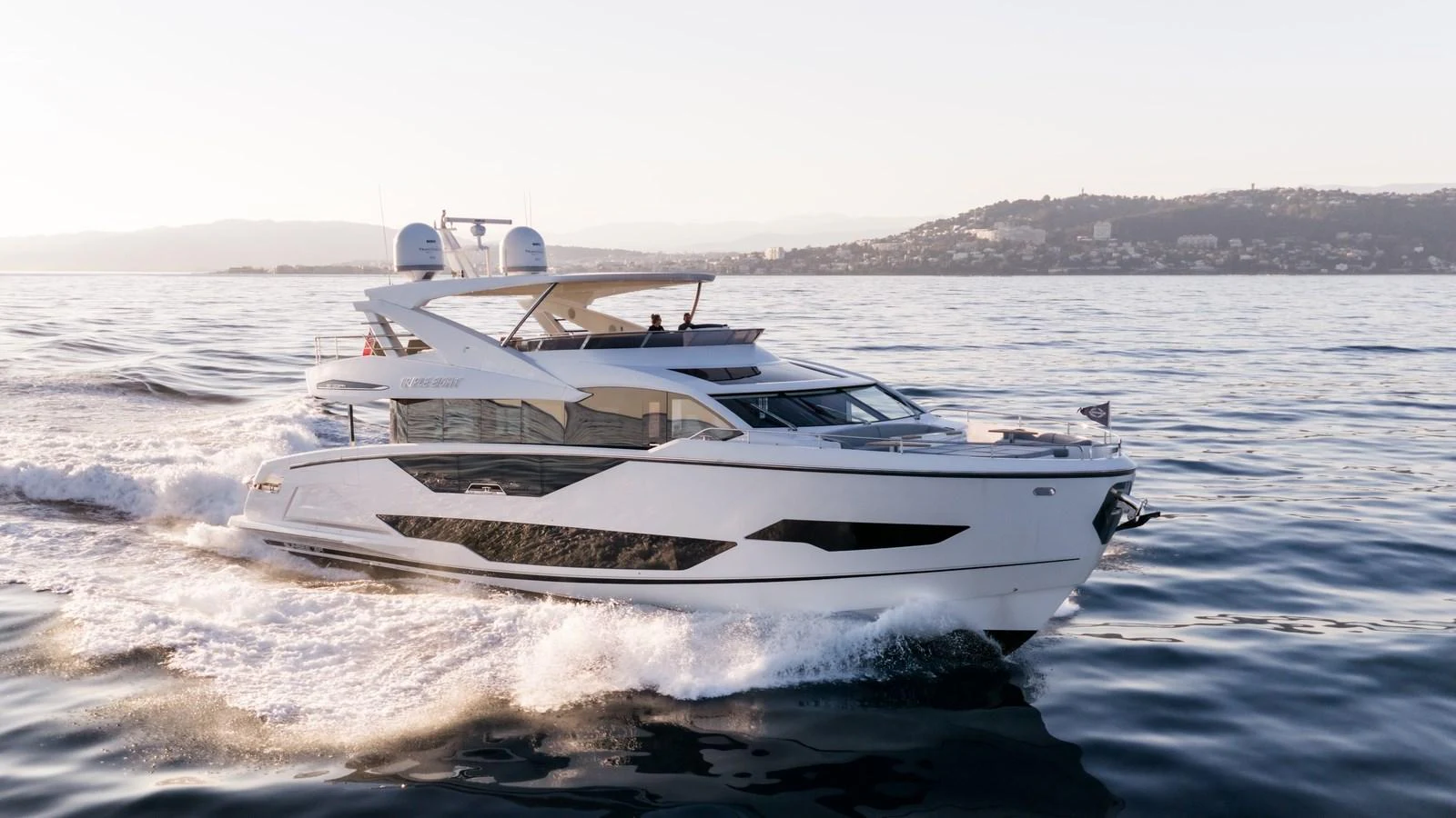 A sleek yacht cruises through calm waters near a coastal city. aboard TRIPLE EIGHT Yacht for Sale